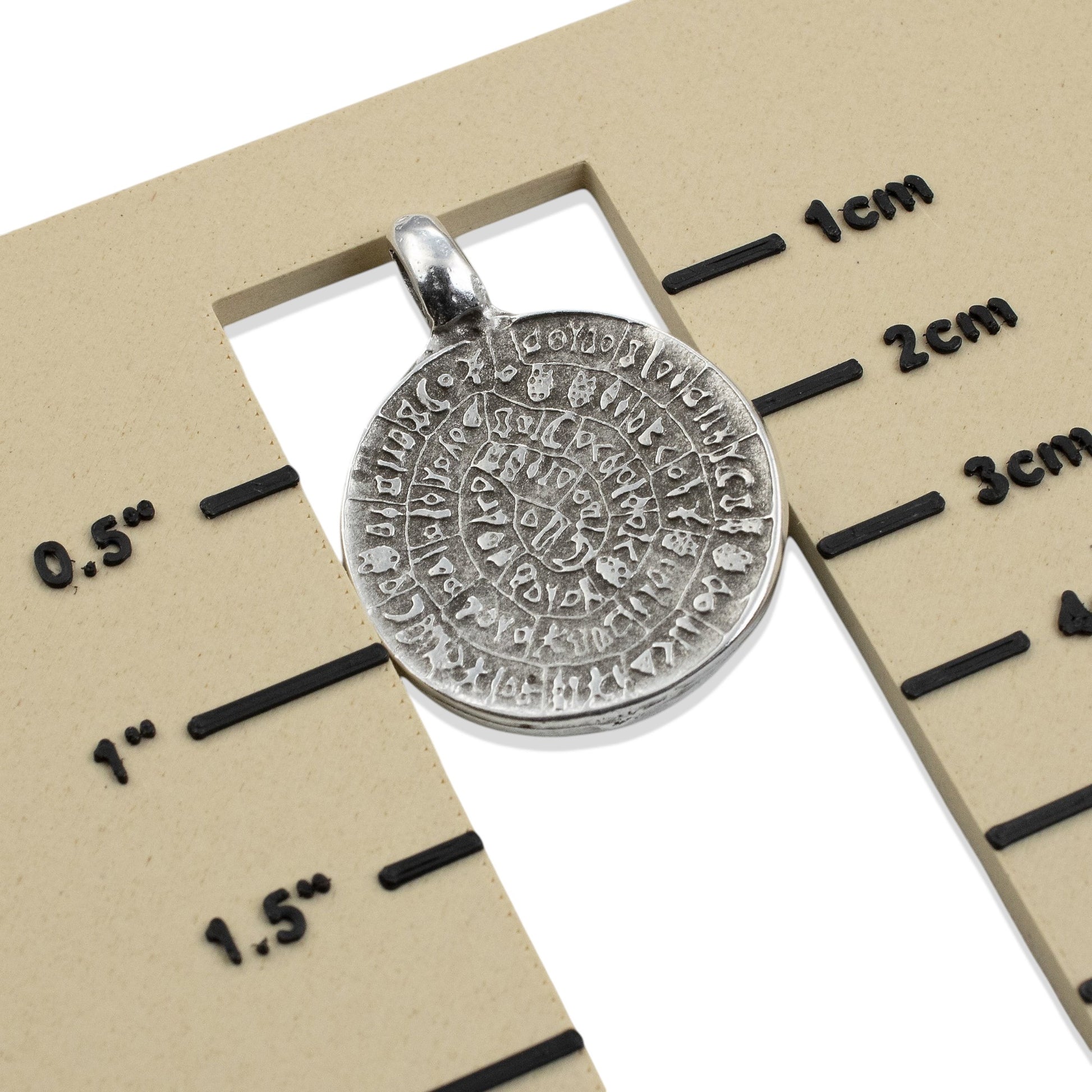 Hackberry Creek silver-plated Zamak Phaistos Disc pendant with spiral script, 25mm, rustic oval shape, made in Greece.