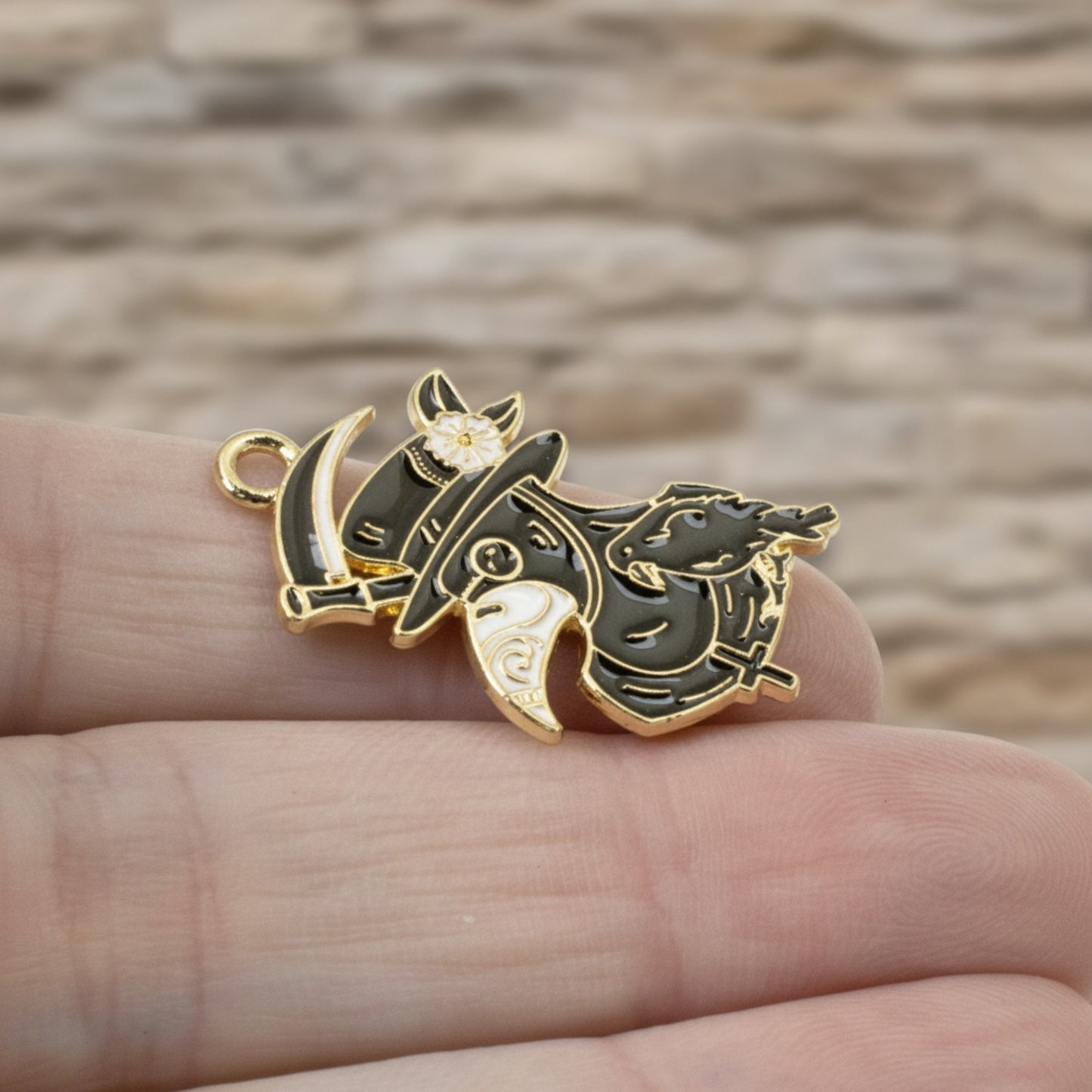 Hackberry Creek plague doctor raven head charm in black and white enamel with gold plating held in hand.