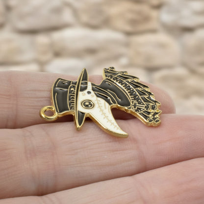 Hackberry Creek plague doctor raven head pendant in black and white enamel with gold plating held in a hand.