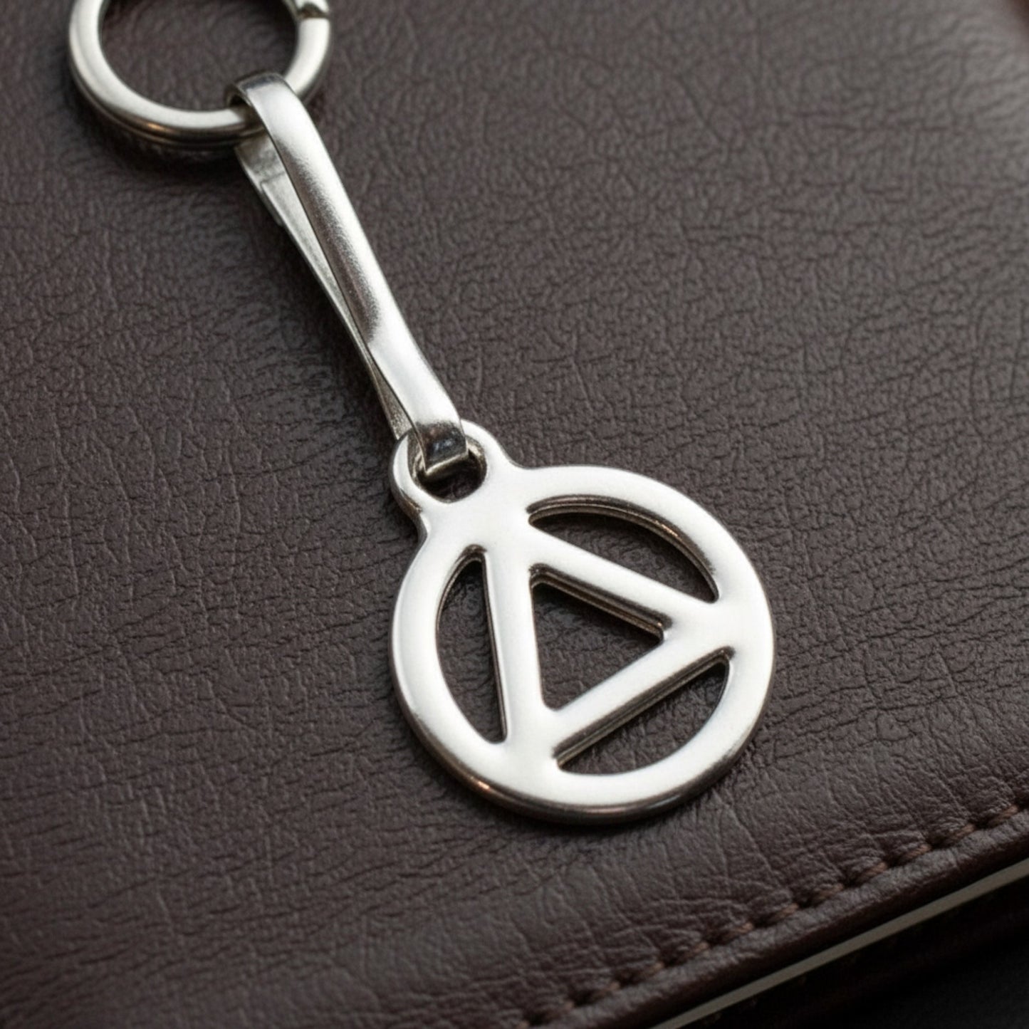 Hackberry Creek silver triangle zipper charm with stainless steel clip, symbolizing recovery and sobriety.
