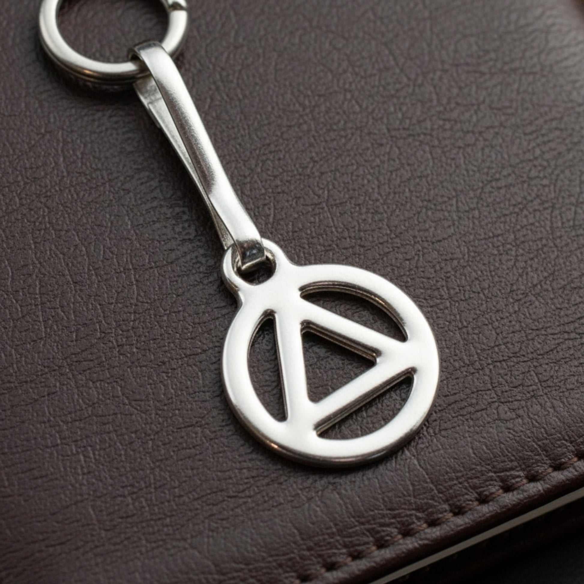 Hackberry Creek silver triangle zipper charm with stainless steel clip, symbolizing recovery and sobriety.
