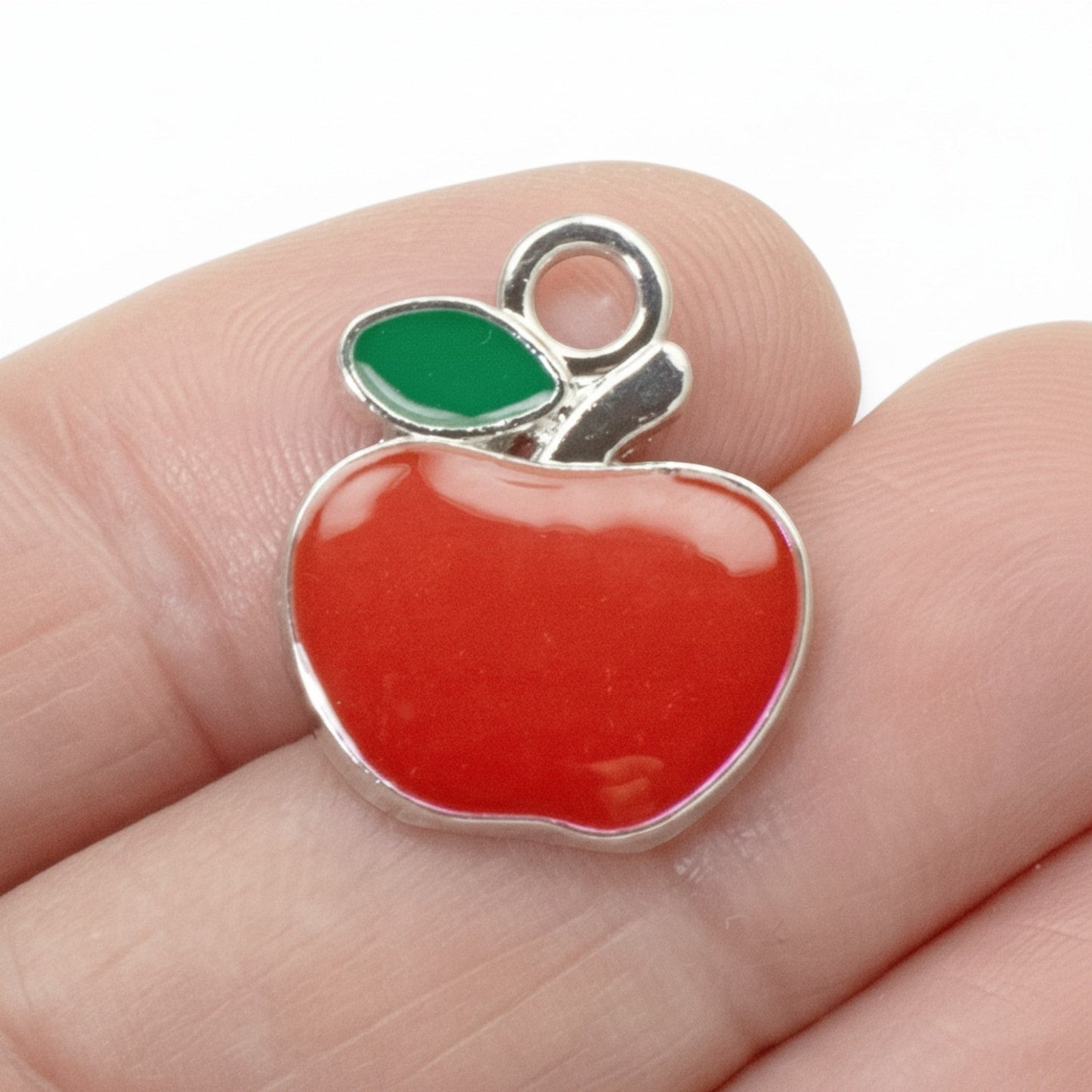 Hackberry Creek bright red enamel apple charm with green leaf and silver loop for jewelry making.