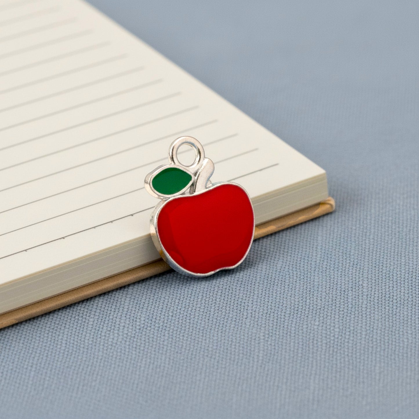 Hackberry Creek bright red enamel apple charm with green leaf detail, silver metal alloy, for jewelry making.