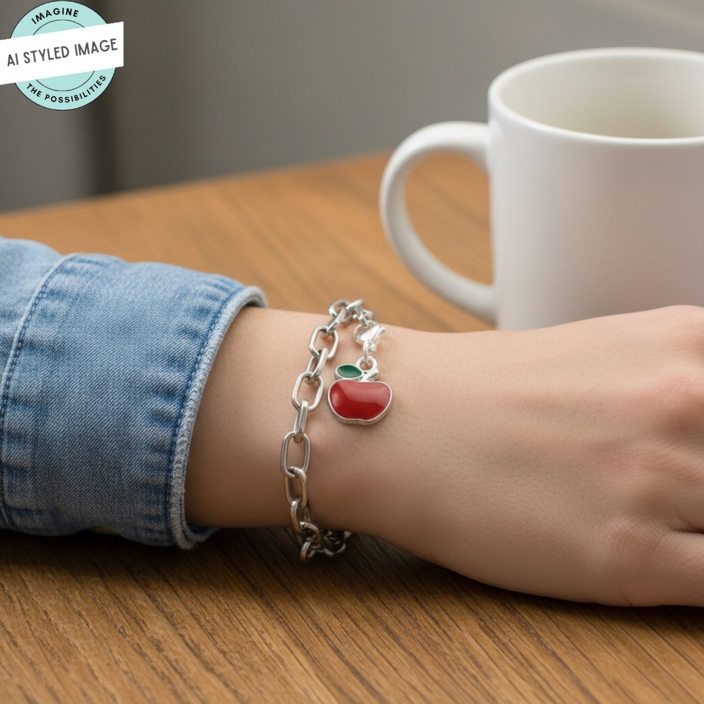 Hackberry Creek red apple charm with green leaf accent, silver-plated brass and enamel, on a silver chain bracelet.