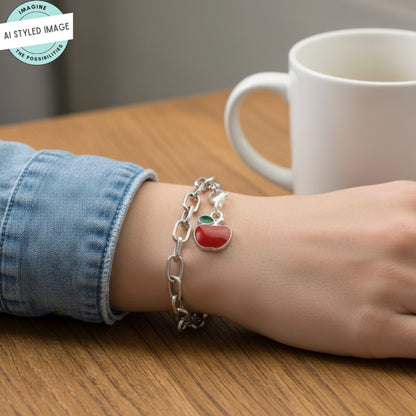 Hackberry Creek red apple charm with green leaf accent, silver-plated brass and enamel, on a silver chain bracelet.