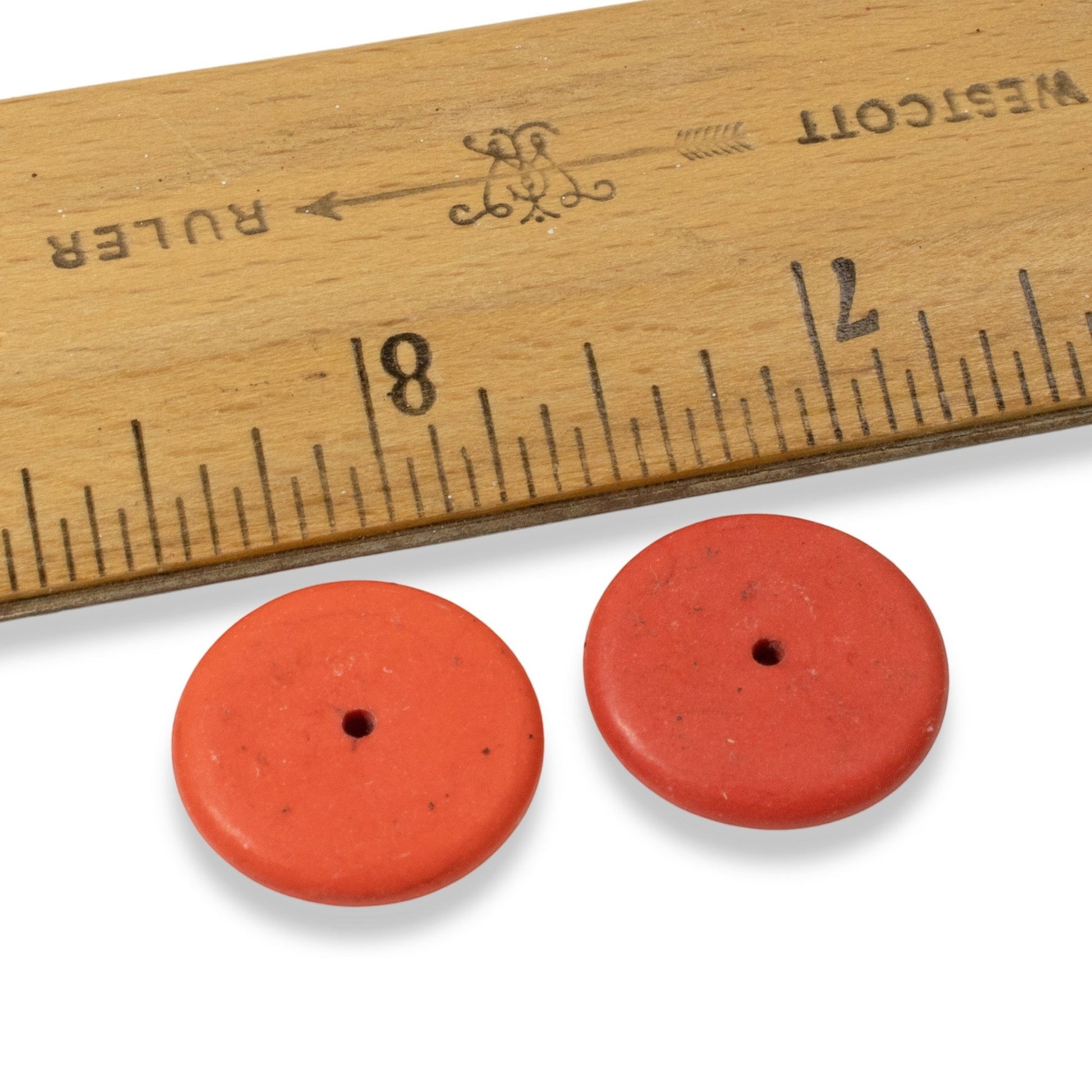 Hackberry Creek muted red magnesite stone rondelle disk beads next to a wooden ruler for size reference