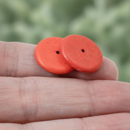 Hackberry Creek muted red magnesite stone rondelle disk beads held in hand for jewelry making