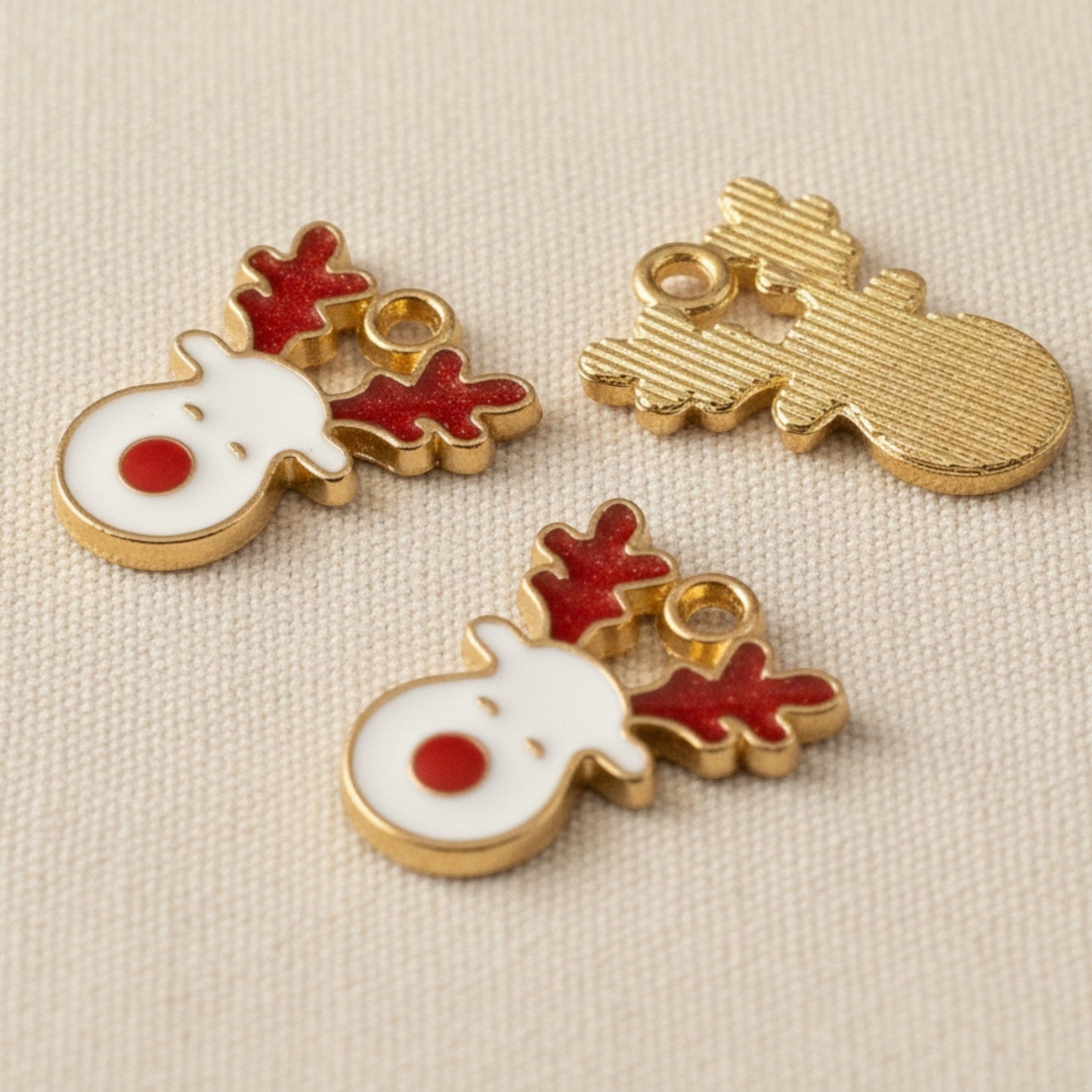 Hackberry Creek red and white enamel reindeer face charms with gold-plated metal finish for Christmas jewelry crafts.