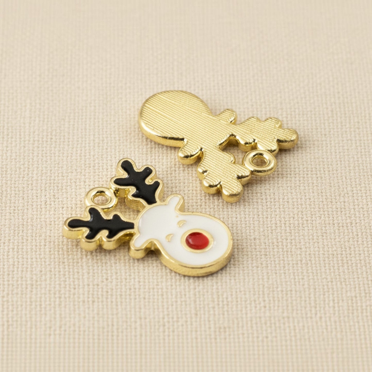 Hackberry Creek reindeer enamel charms with white face, red nose, and black antlers on a gold-plated metal base.