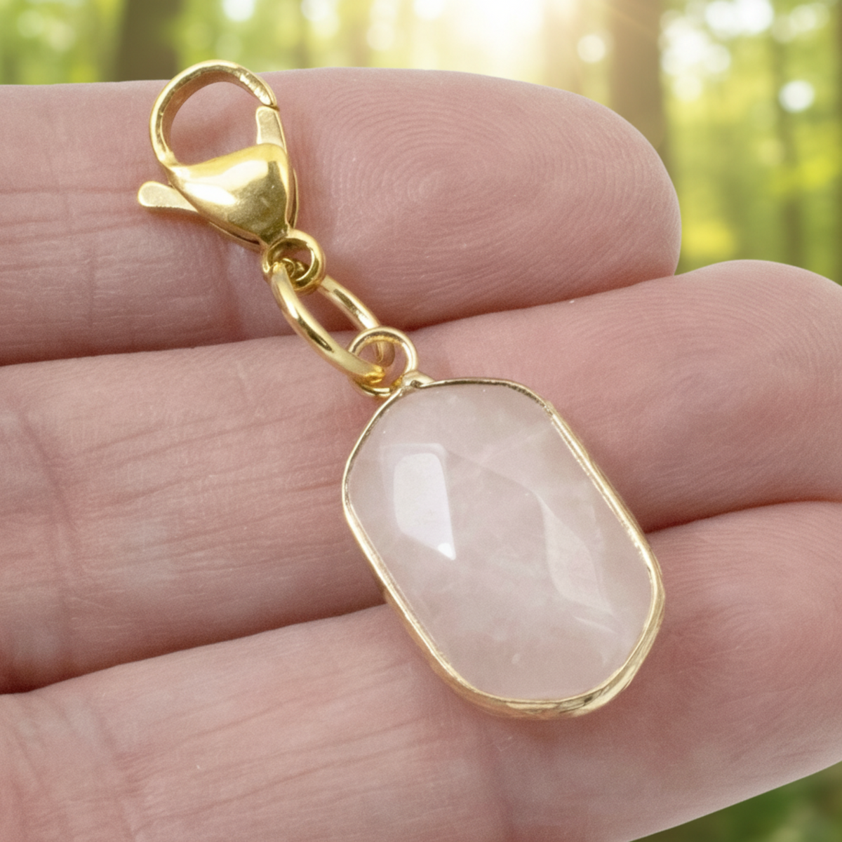 Hackberry Creek faceted oval rose quartz charm with gold-plated lobster clasp held in a hand