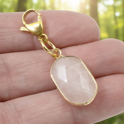 Hackberry Creek faceted oval rose quartz charm with gold-plated lobster clasp held in a hand
