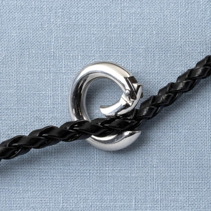 Hackberry Creek 15mm round stainless steel carabiner spring clasp securing a black braided leather cord