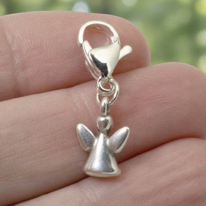 Hackberry Creek silver angel clip-on charm held between fingers, a delicate memorial gift with a lobster clasp.