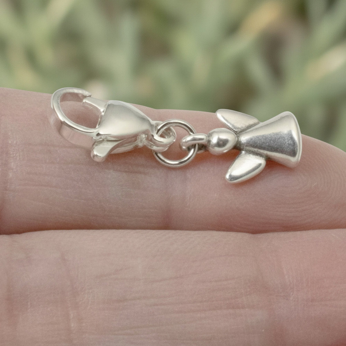Hackberry Creek silver guardian angel charm with a stainless steel lobster clasp held on a person's finger