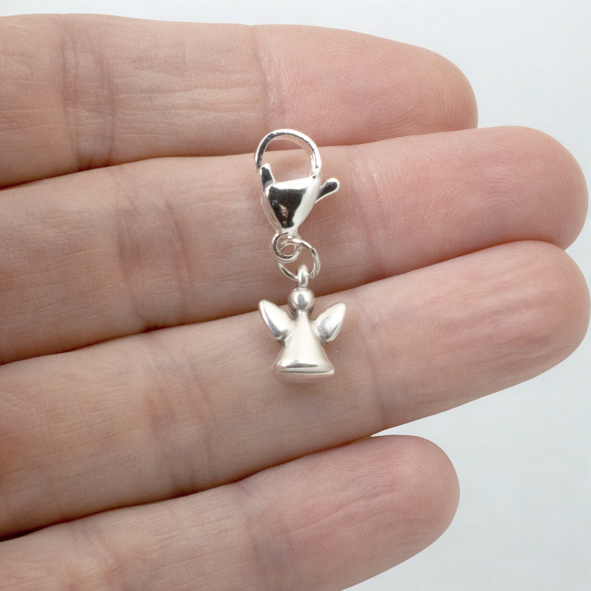 Hackberry Creek silver guardian angel charm with a lobster clasp held in a hand for scale