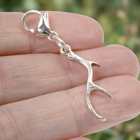Hackberry Creek silver antler clip-on charm with a lobster clasp held against a blurred nature background