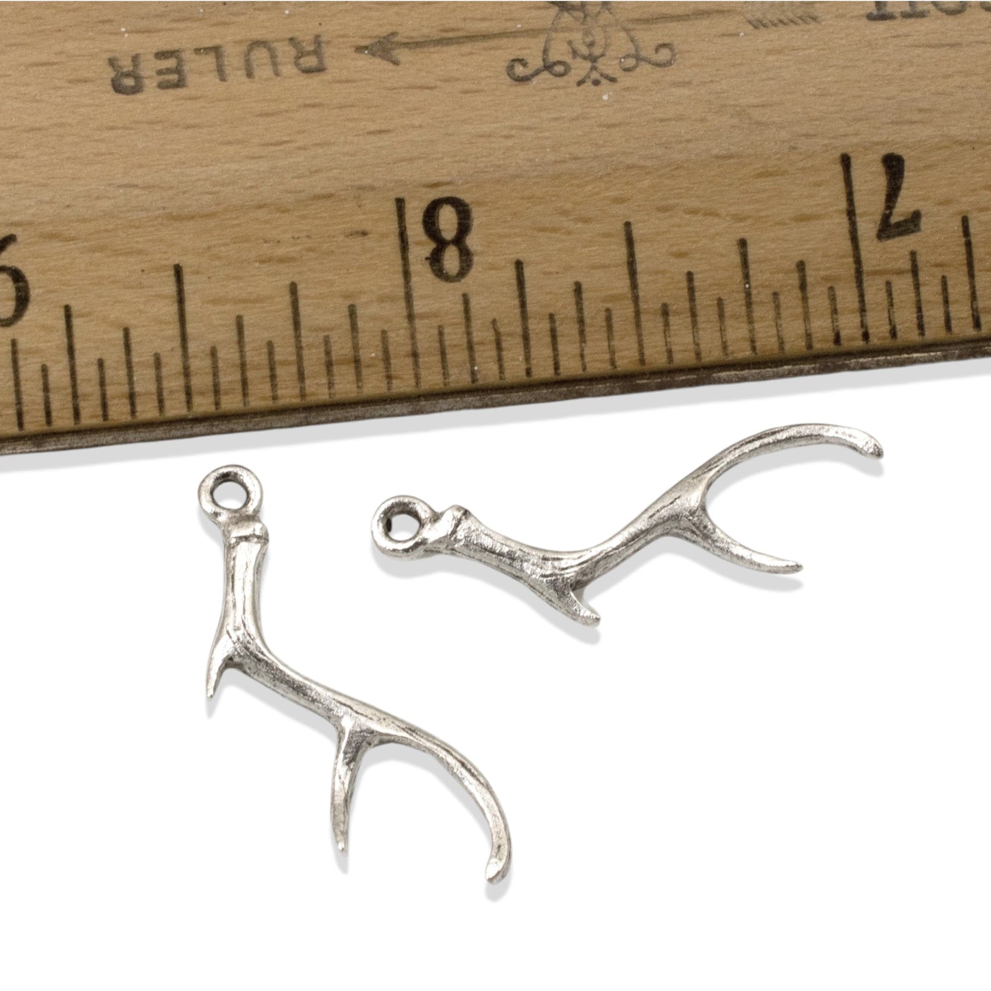 Hackberry Creek Nunn Design silver plated pewter antler charms for jewelry making, shown next to a ruler for scale.