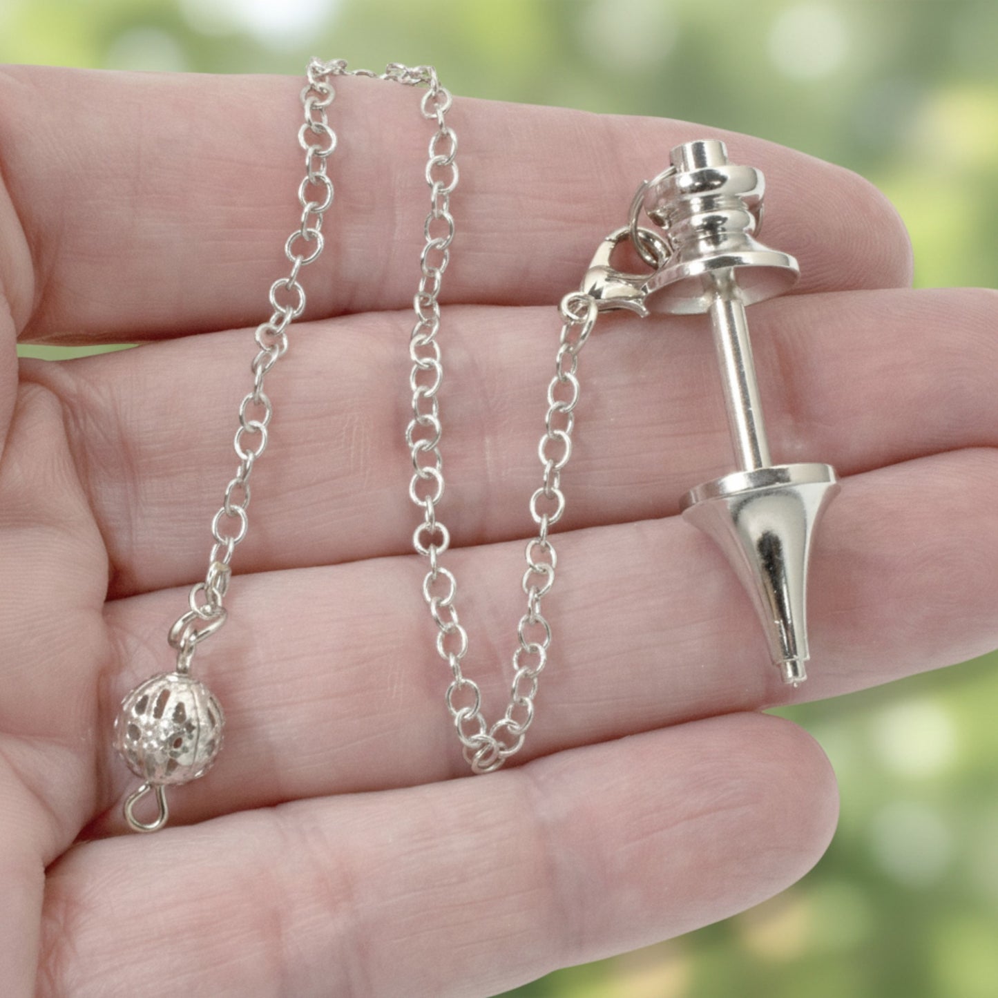 Hackberry Creek silver zinc alloy beadable pendulum with a detachable chain held in a hand for DIY jewelry crafting.