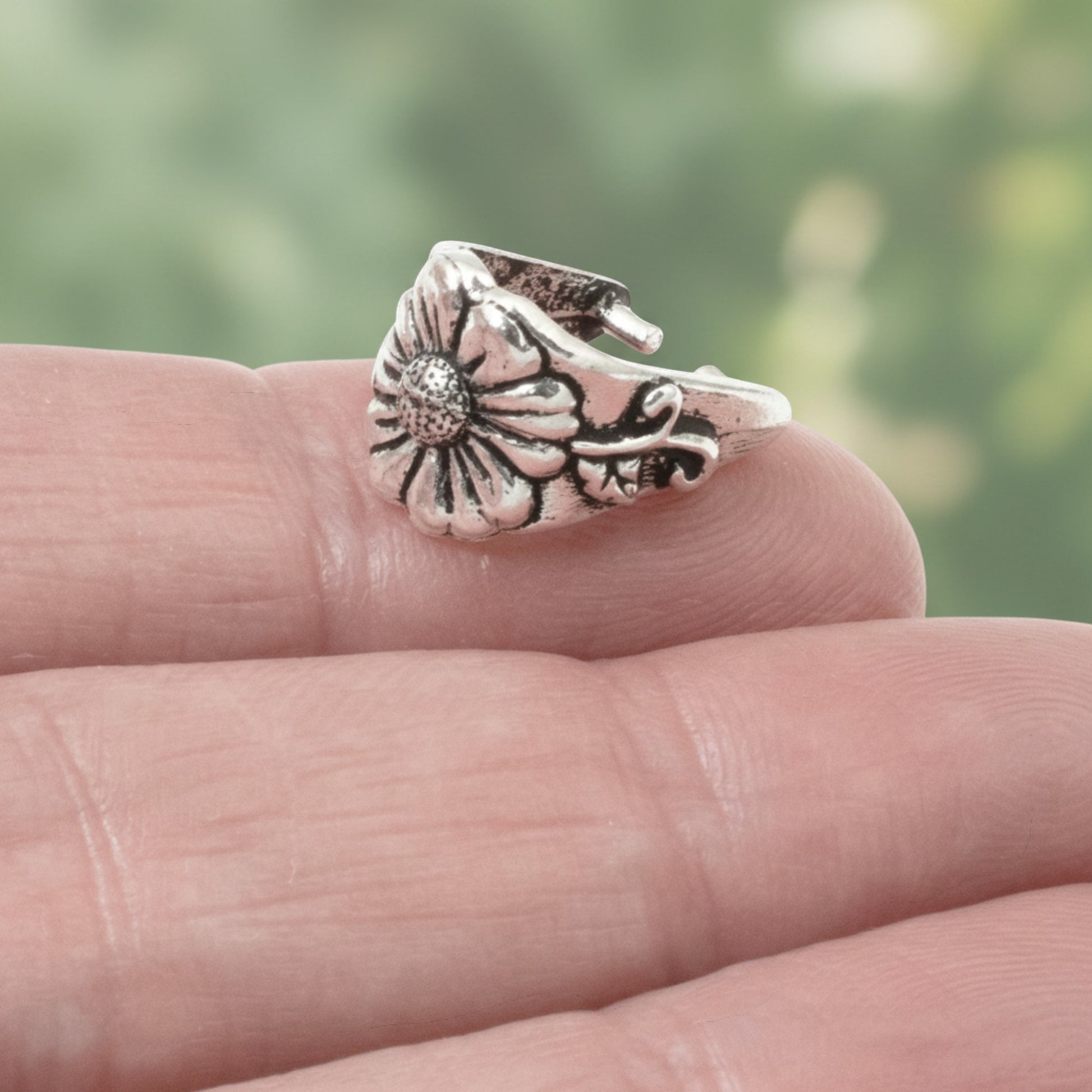 Hackberry Creek TierraCast antique silver pinch bail with floral vine design held on a fingertip