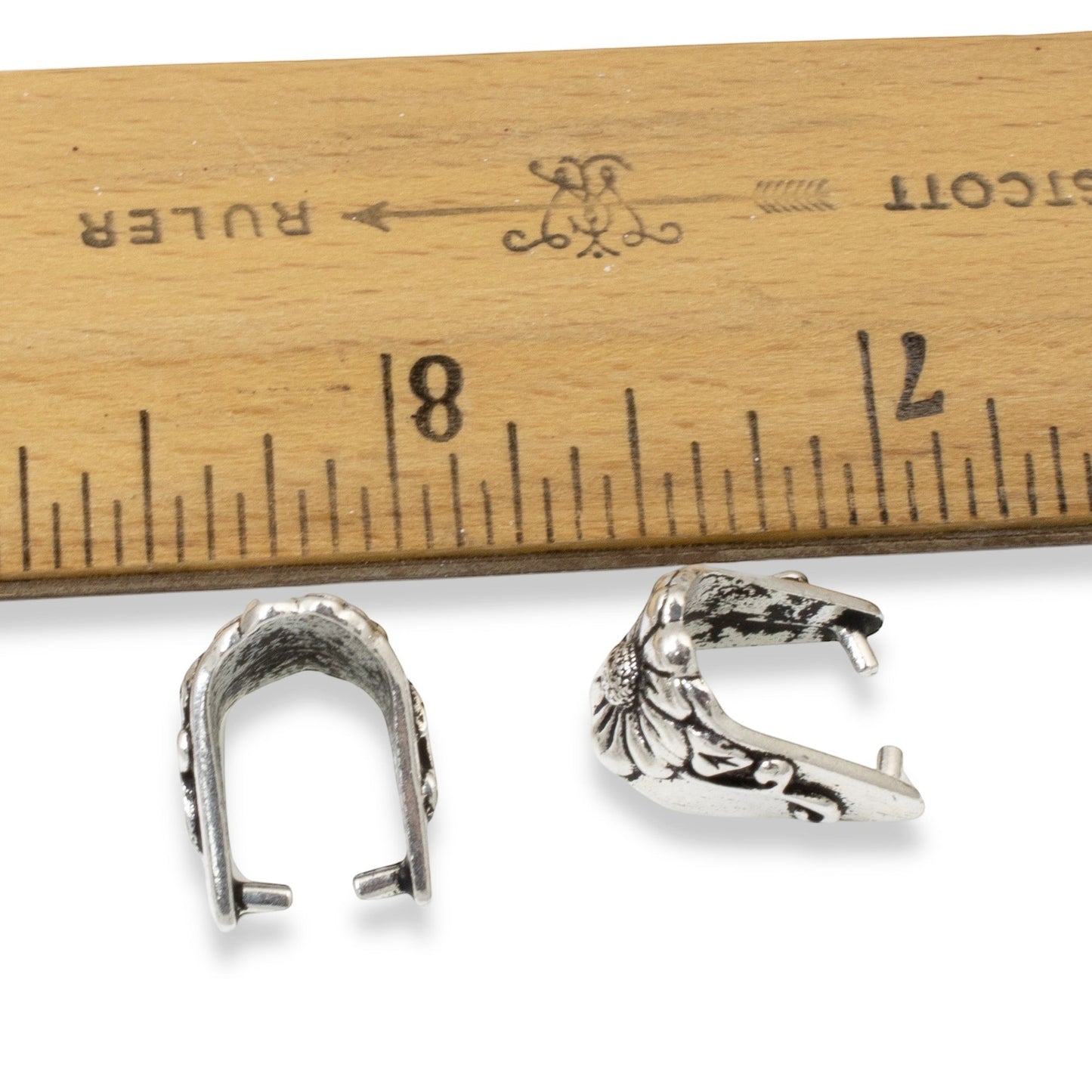 Hackberry Creek TierraCast antique silver pinch bails with floral vine design next to a ruler for scale