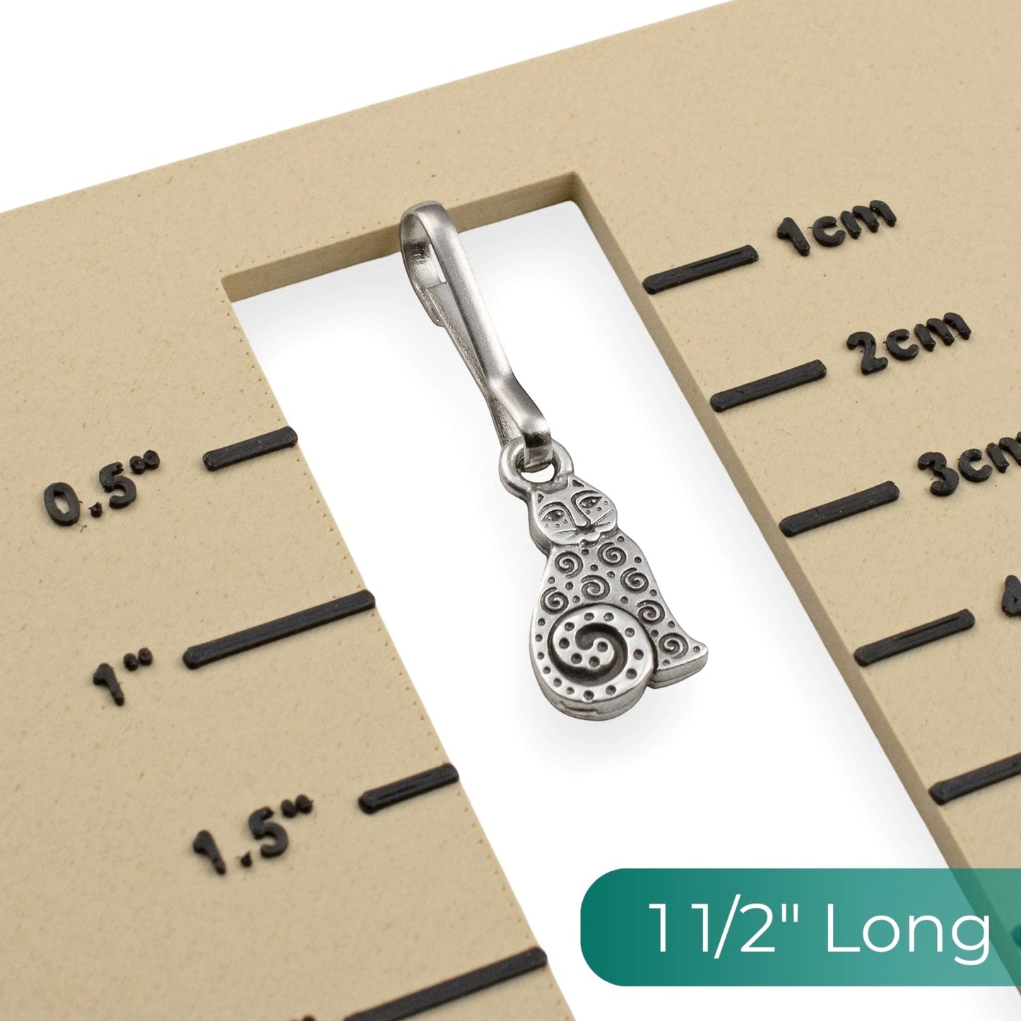 Hackberry Creek silver-plated pewter sitting cat zipper charm with spiral details on a 1.5-inch scale measurement card.
