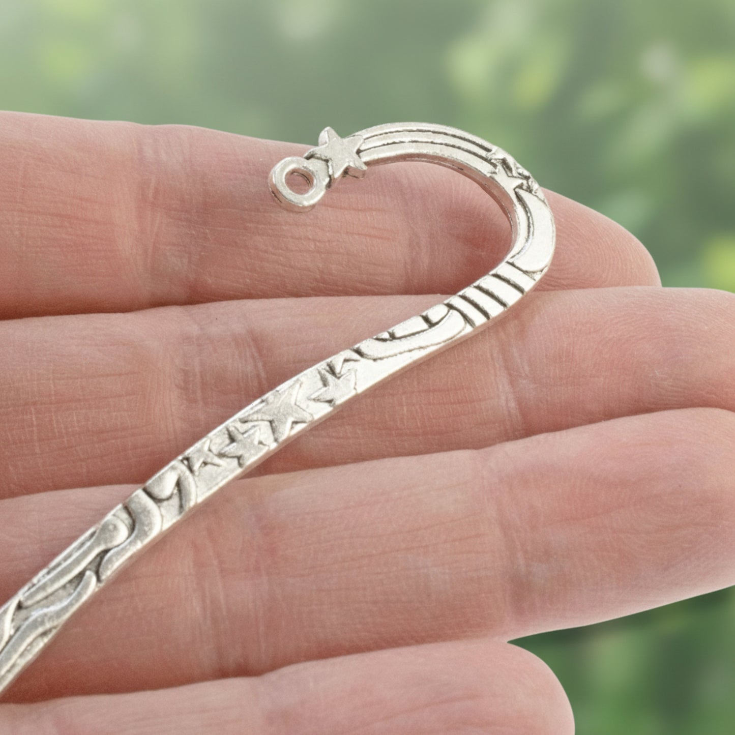 Hackberry Creek antique silver zinc alloy hook bookmark with celestial star and sun engravings held in a hand