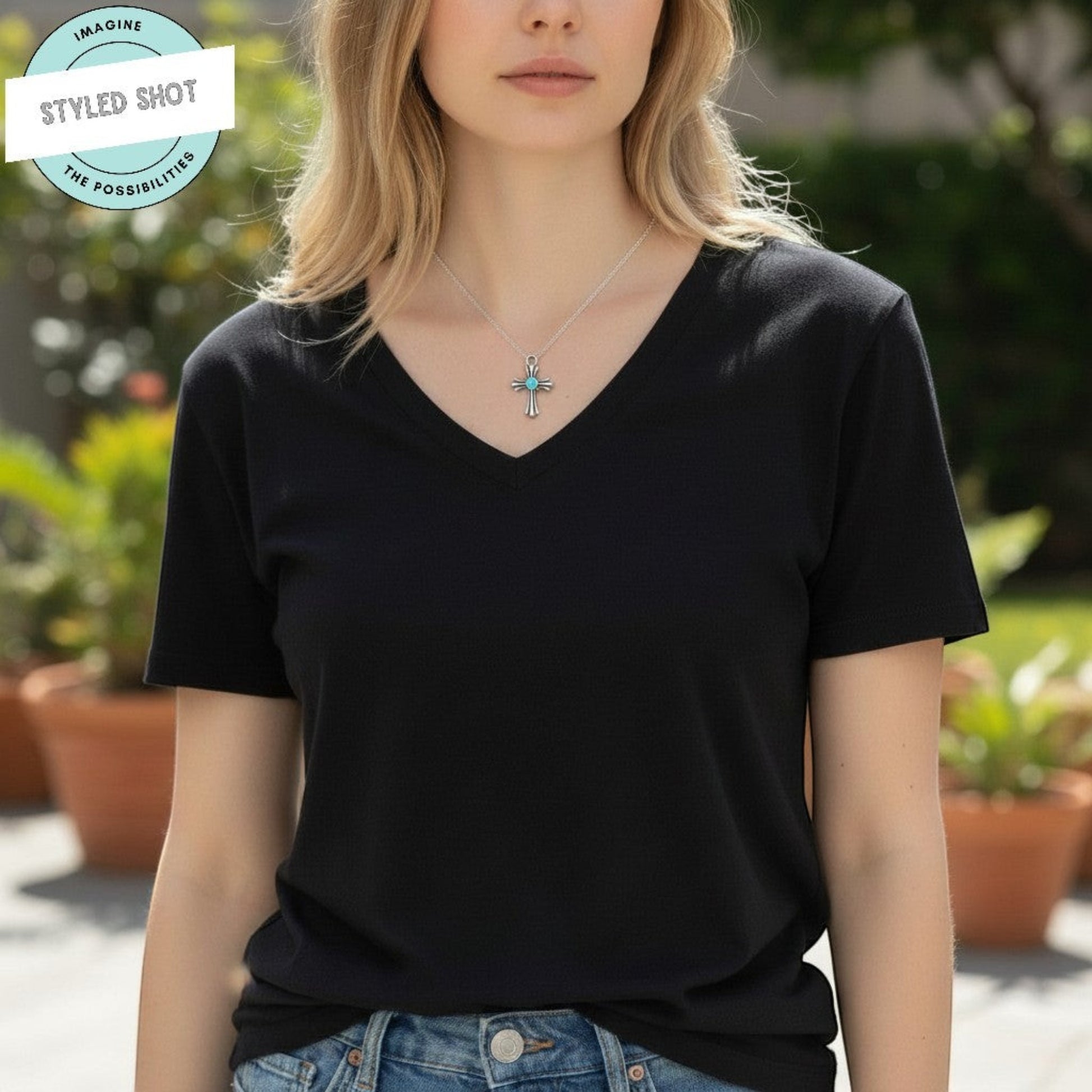 Hackberry Creek silver plated cross pendant with aqua enamel accent, art deco design, on a silver chain worn by a woman.