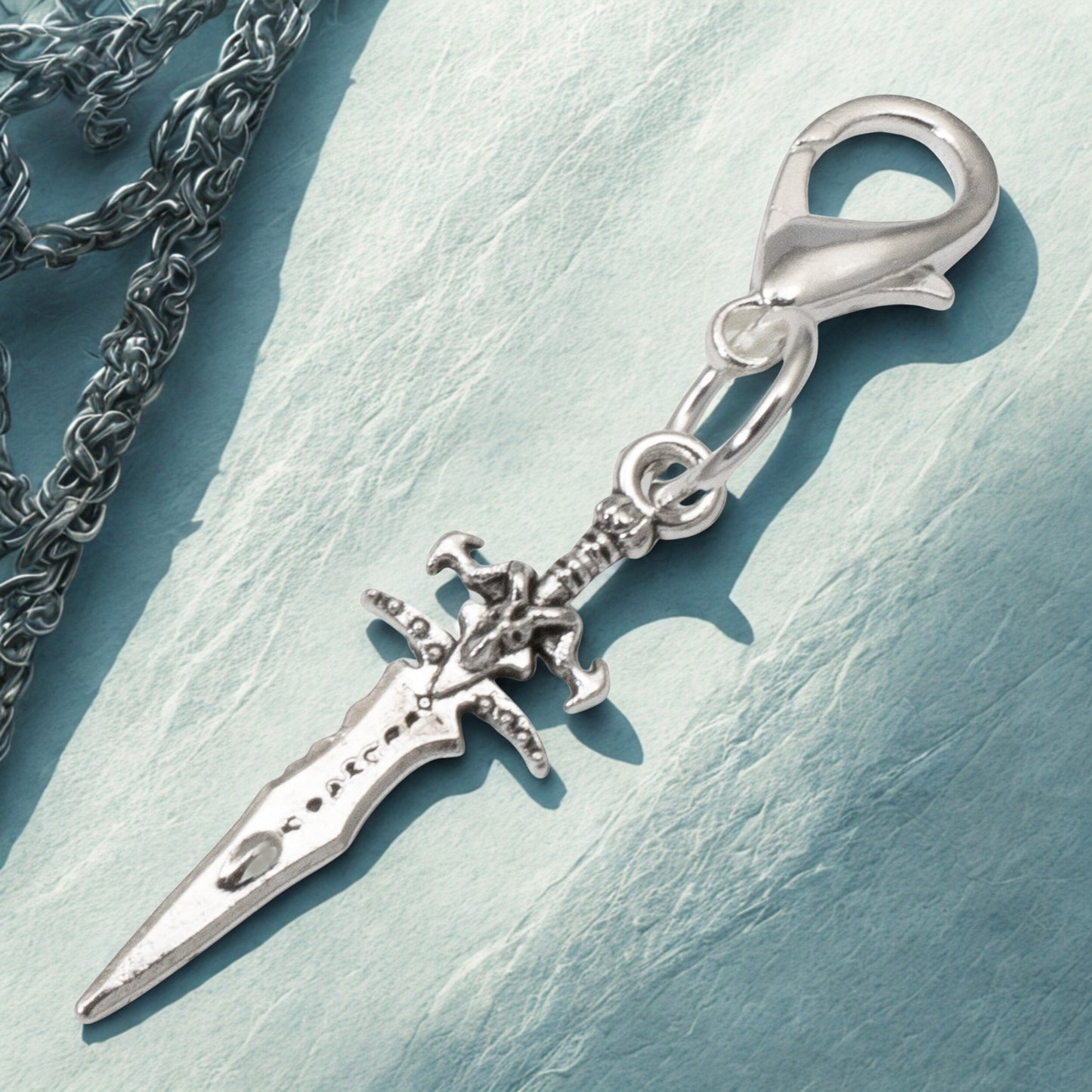 Hackberry Creek silver metal alloy dagger charm with intricate detailing and lobster clasp, 1 3/4" long.