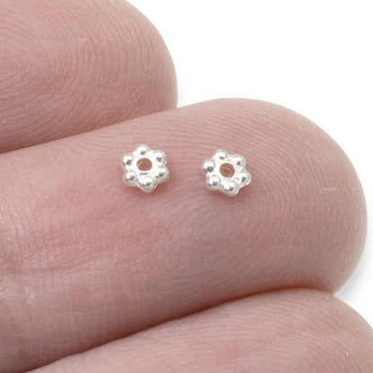 Hackberry Creek 3mm bright silver plated pewter daisy heishi spacer beads. Small floral beads with a polished finish.