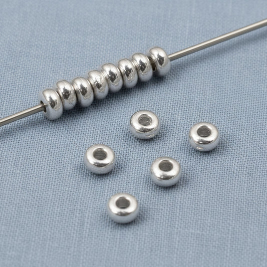 Hackberry Creek shiny silver 3mm disk beads, made of pewter with .999 fine silver plating. Smooth heishi spacers for jewelry making.
