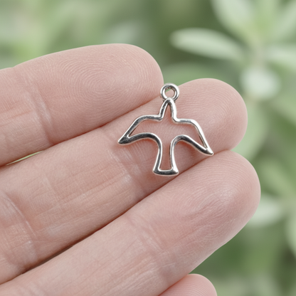 Hackberry Creek silver peace dove charm with an open silhouette design held between fingers