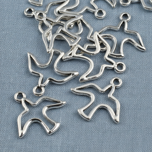 Hackberry Creek silver peace dove charms with an open silhouette design for jewelry making on a blue fabric background
