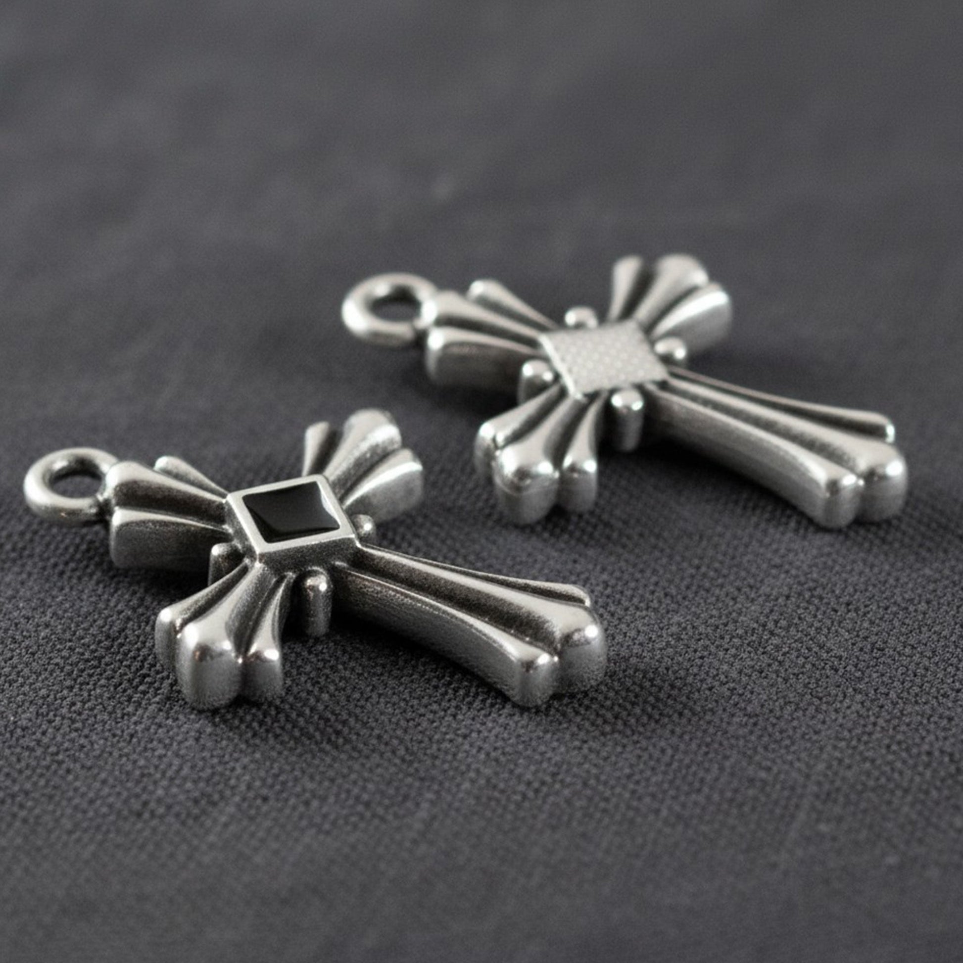 Hackberry Creek silver plated gothic cross pendants with black enamel center accents on a dark fabric background.