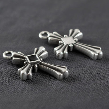 Hackberry Creek silver plated gothic cross pendants with black enamel center accents on a dark fabric background.