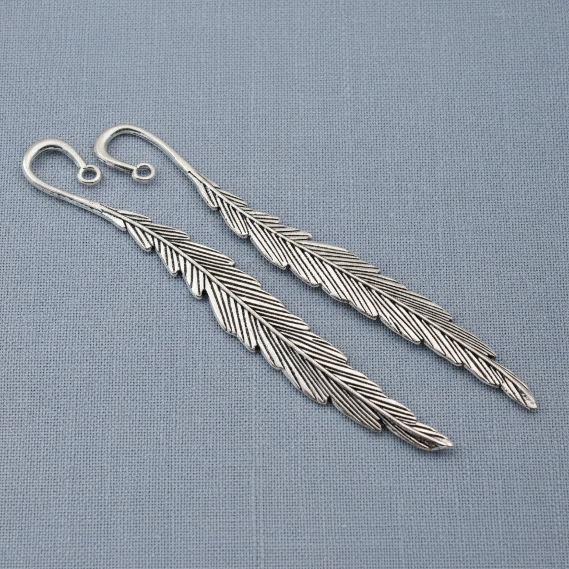 Hackberry Creek silver feather bookmark bases with etched detail and charm loops for DIY craft projects.