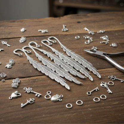 Hackberry Creek silver feather bookmark bases with assorted charms and pliers on a rustic wooden table