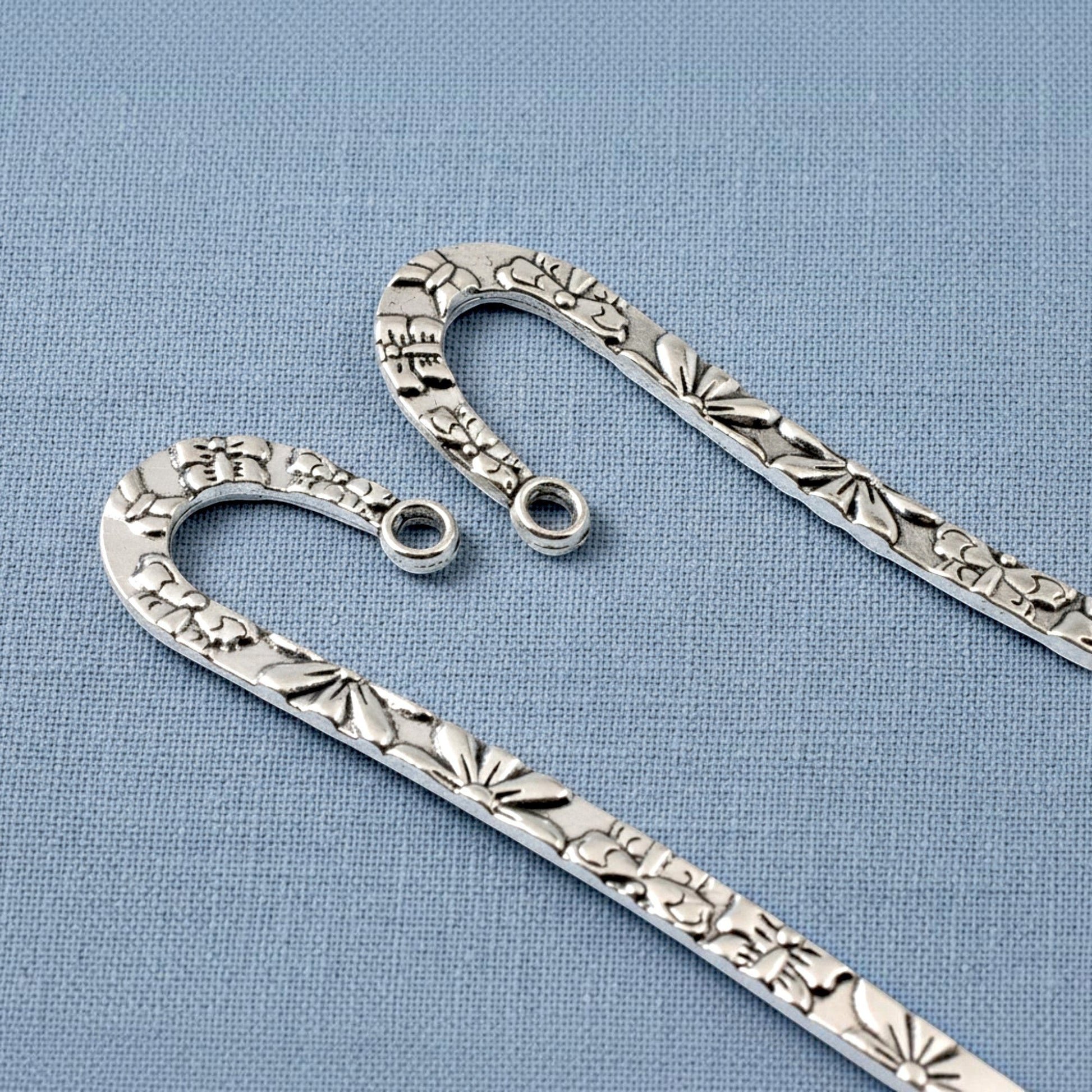 Hackberry Creek silver zinc alloy hook bookmarks with raised floral and butterfly patterns for DIY jewelry projects.