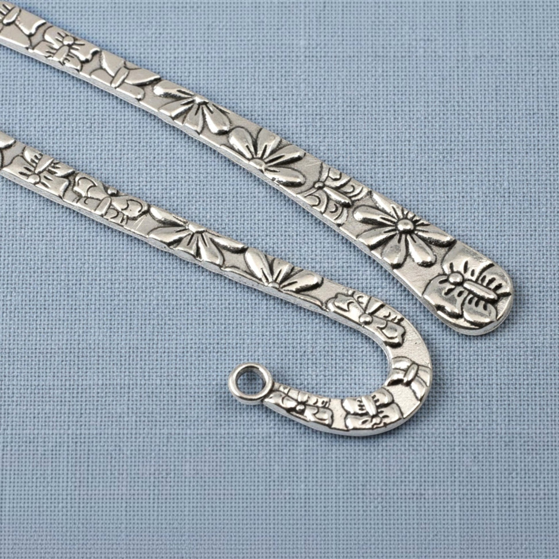 Hackberry Creek silver zinc alloy hook bookmarks with raised floral and butterfly patterns for DIY jewelry projects.