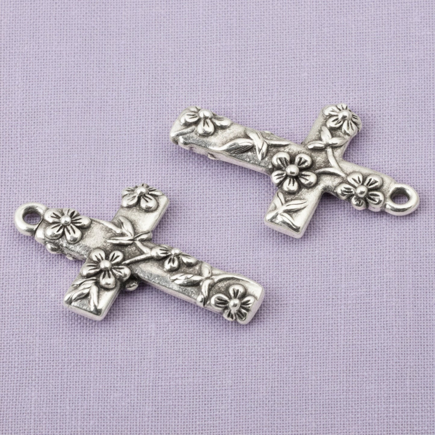 Hackberry Creek silver-plated pewter floral cross pendants with intricate raised flower details for jewelry making.