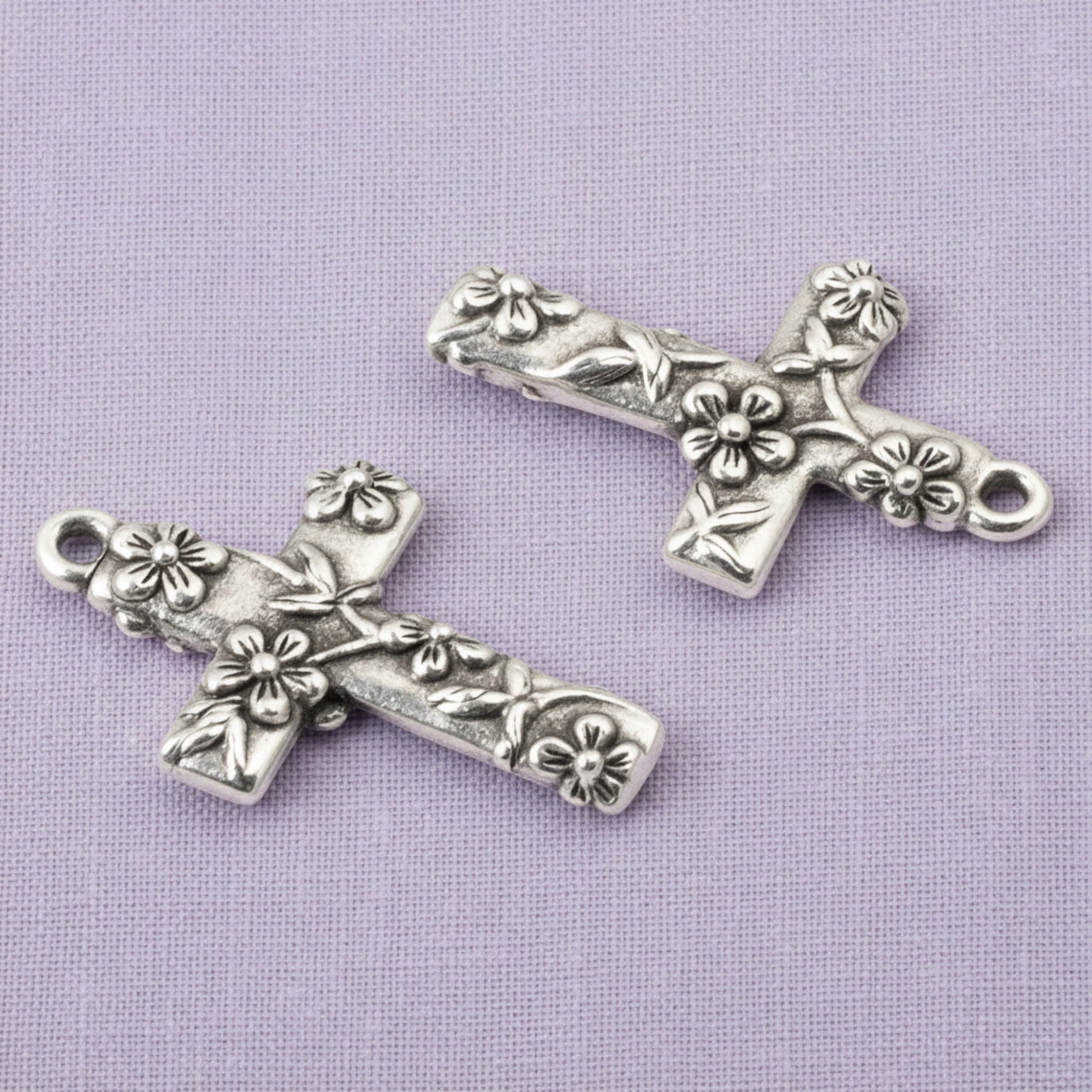 Hackberry Creek silver-plated pewter floral cross pendants with intricate raised flower details for jewelry making.