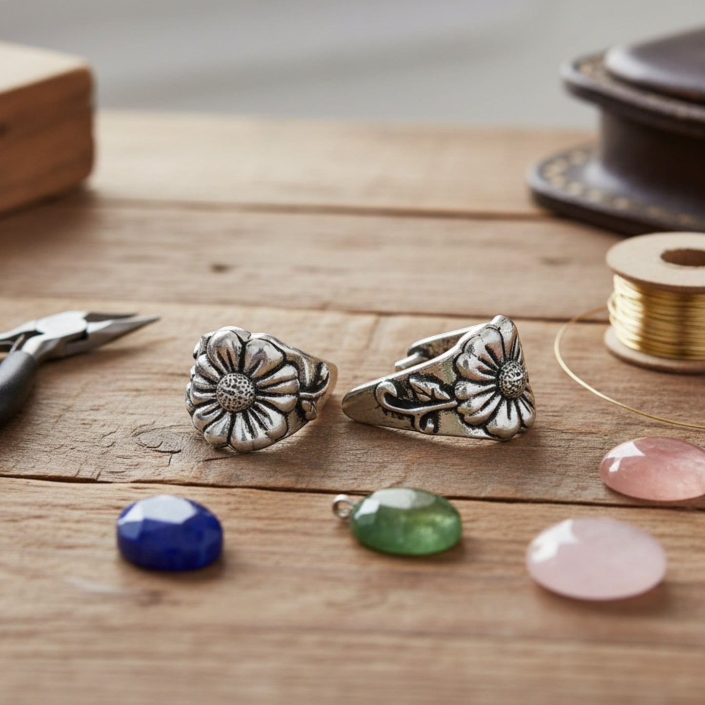 Hackberry Creek TierraCast antique silver pinch bails with flower and vine design on a wooden jewelry making table
