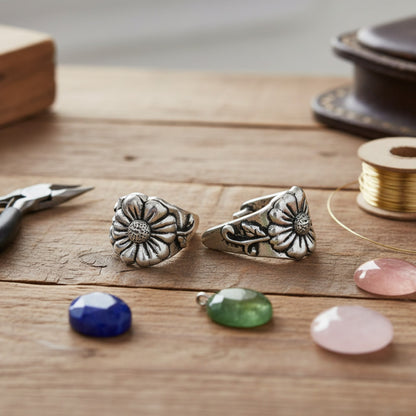 Hackberry Creek TierraCast antique silver pinch bails with flower and vine design on a wooden jewelry making table