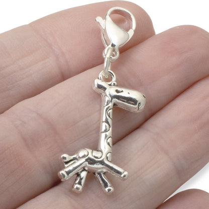 Hackberry Creek silver giraffe charm with a stainless steel lobster clasp held in a hand for scale
