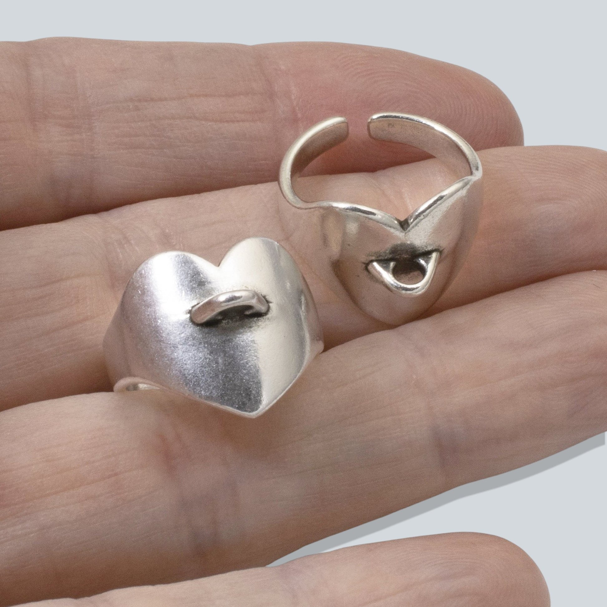 Hackberry Creek silver-plated heart-shaped adjustable ring bases with charm loops held in a hand.