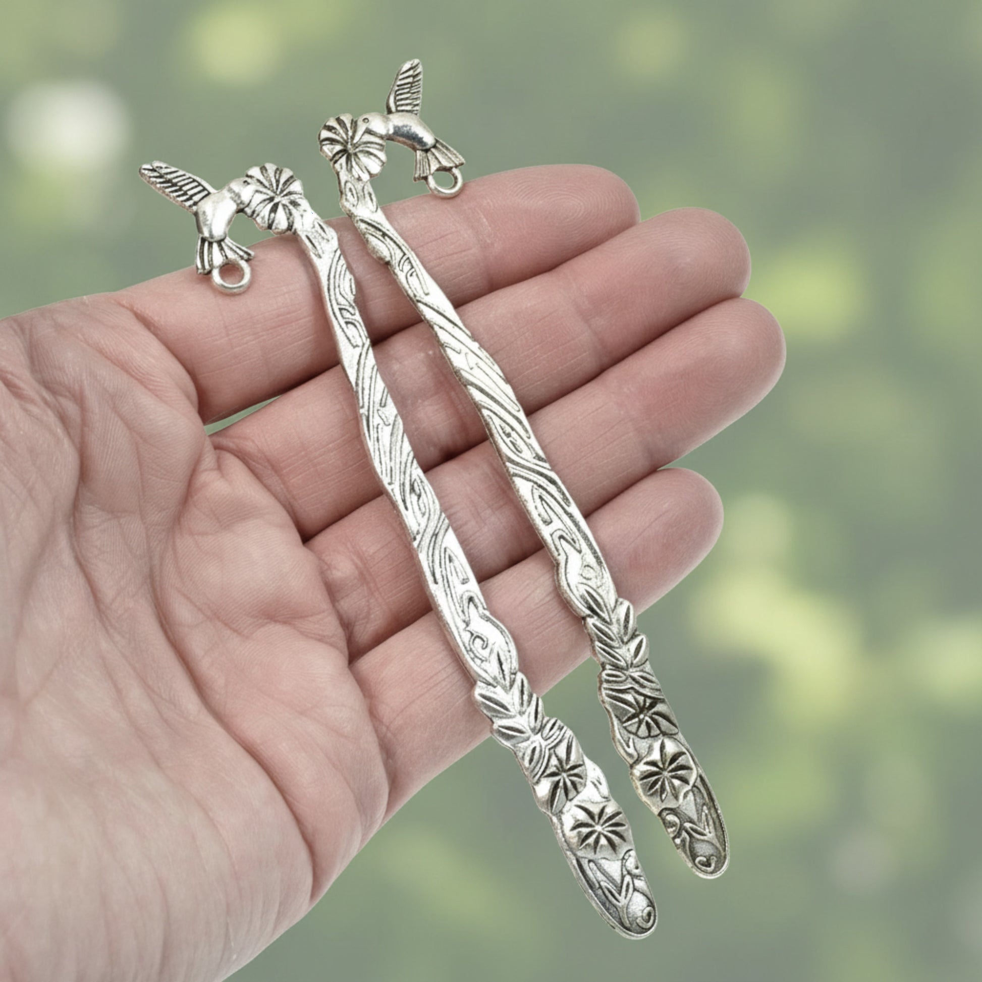 Hackberry Creek antique silver metal bookmark blanks featuring hummingbird and flower designs held in a hand