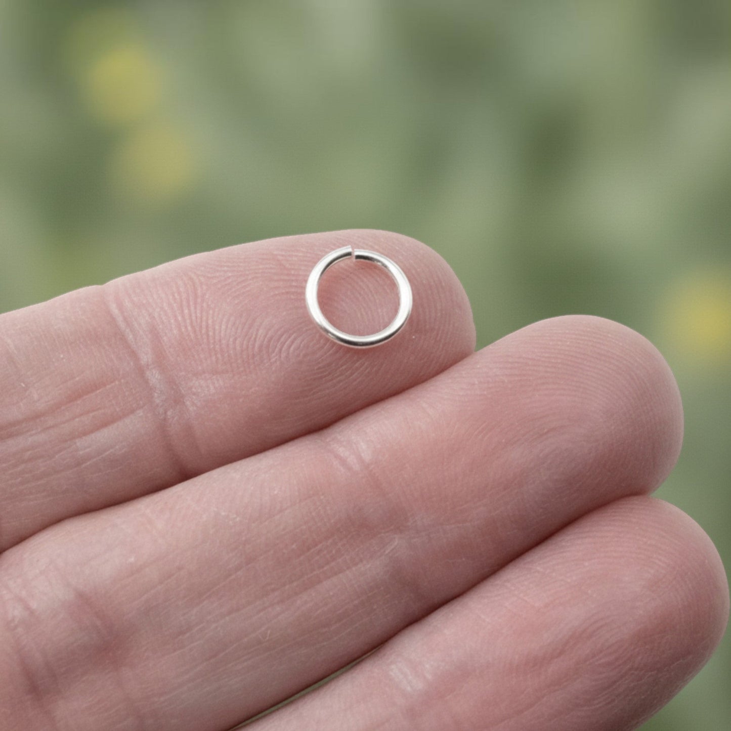 Hackberry Creek 8mm silver plated brass jump ring held on a fingertip for scale