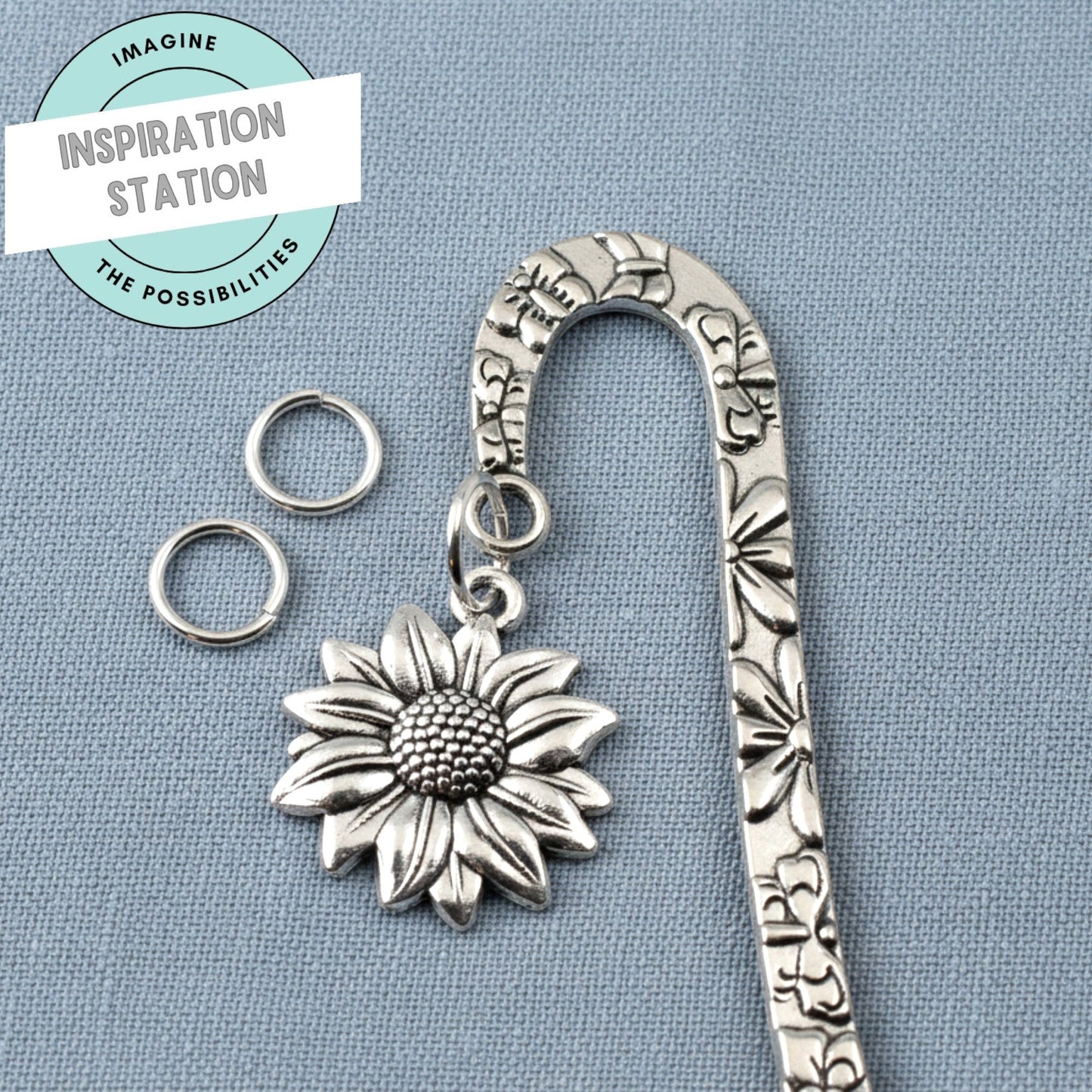 Hackberry Creek 8mm silver plated brass jump rings next to a sunflower charm on a metal bookmark
