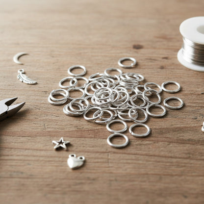Hackberry Creek 8mm silver plated brass jump rings for jewelry making on a wooden table with charms and pliers