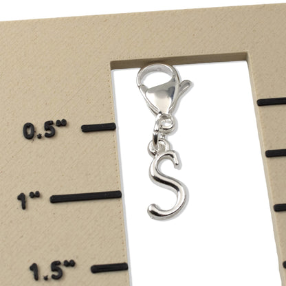 Hackberry Creek silver cursive letter S charm with a lobster clasp shown against a ruler for scale.
