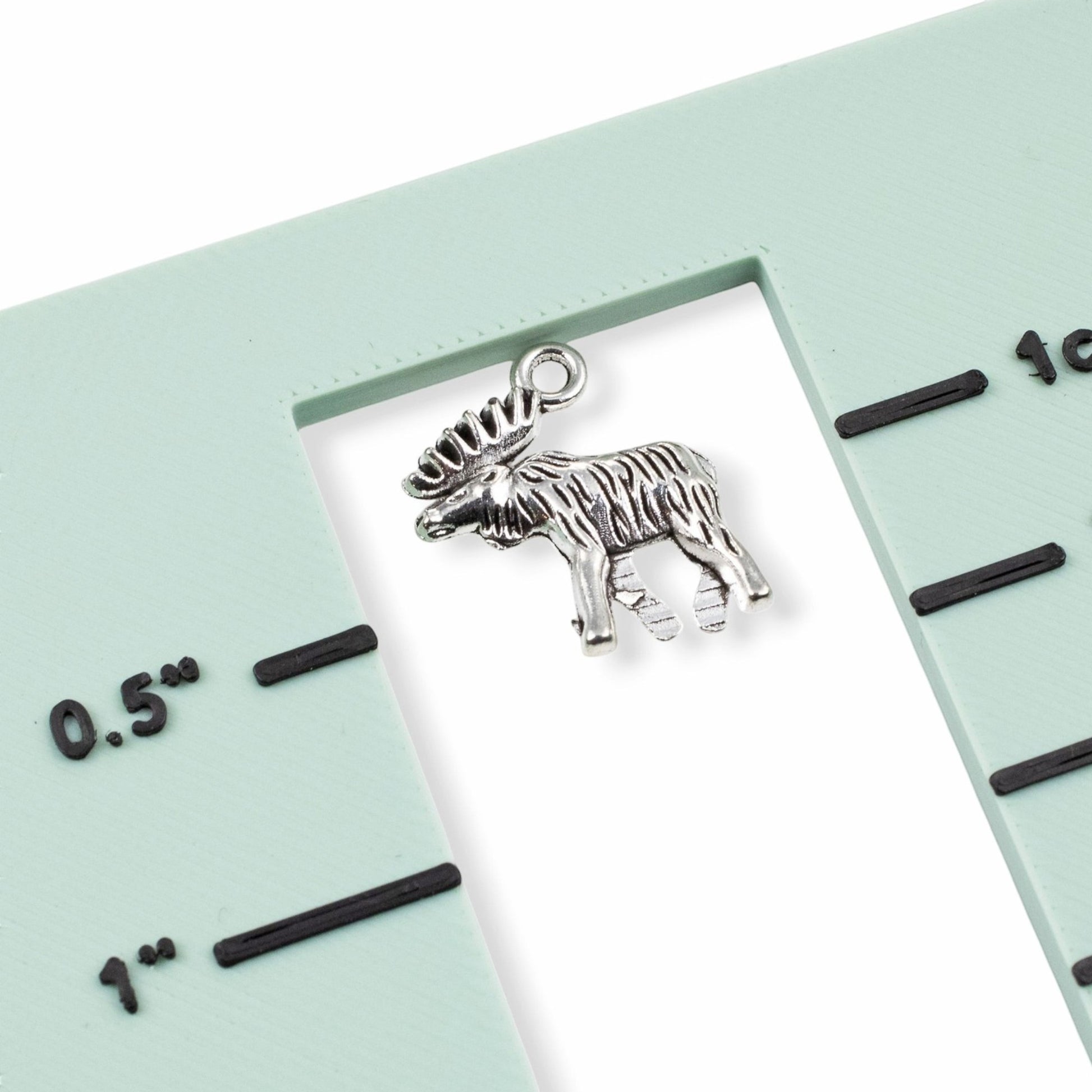 Hackberry Creek silver moose charm pendant with detailed walking design on a measuring tool for scale